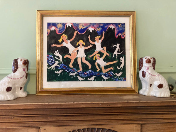 A close up mock up of the art print which clearly shows the blue sky with yellow stars, black mountains topped with pink and the girls dancing on the green grass with their white cats and birds.