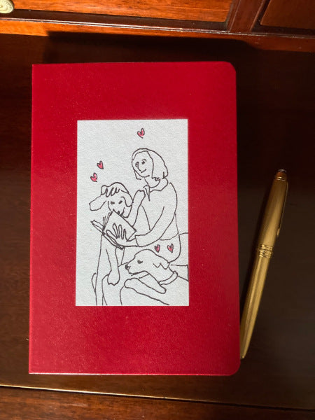 Mockup of On Being Idolized printed on a red journal sitting on a wooden table.