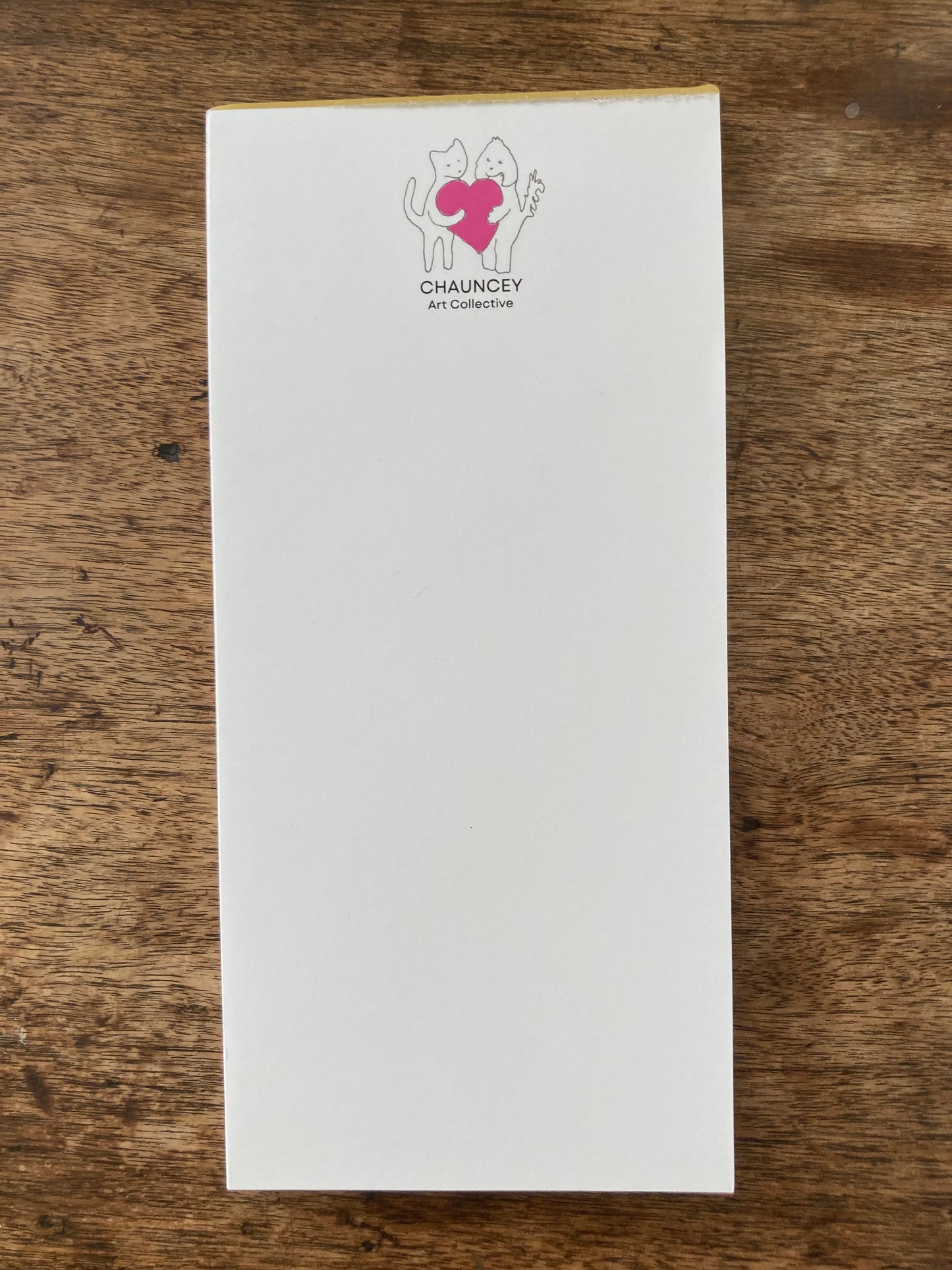 A mockup of the Chauncey Art Collective logo magnetic notepad atop wooden table.