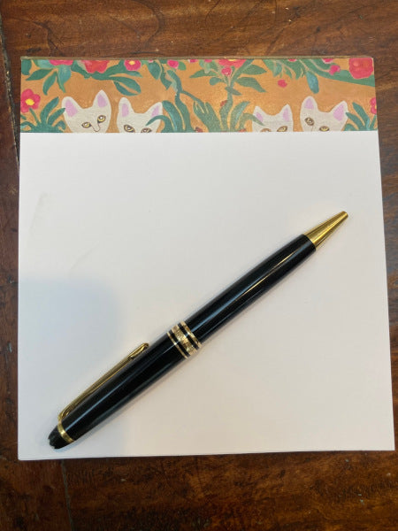 This notepad features a banner of Curious Cats who are peeking out of the foliage to see you.  Set against a taupe background, the white cat faces stand out as do the green leaves and pink flowers