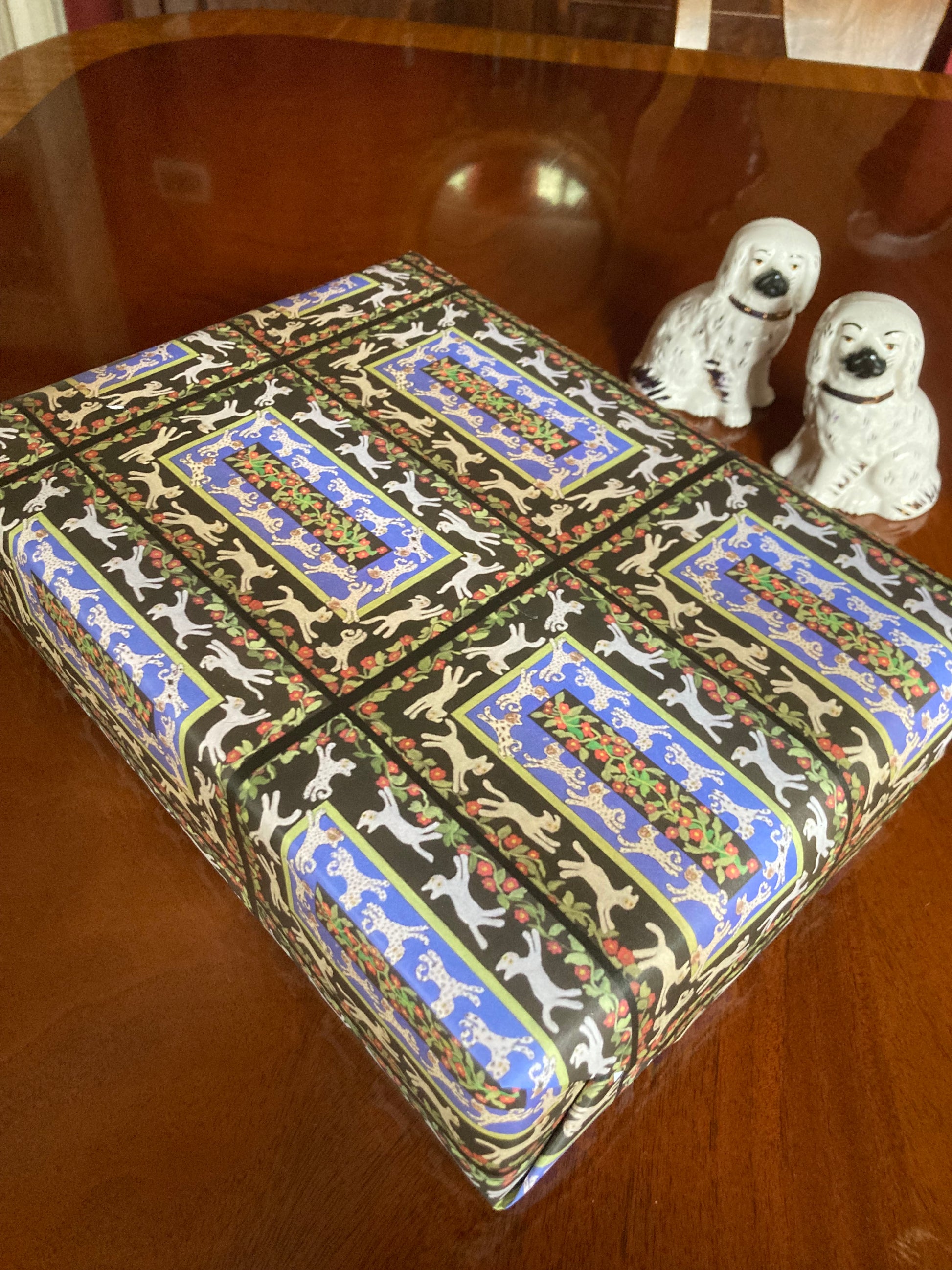Mock up of Cats In The Garden wrapping paper next to 2 Staffordshire dogs.