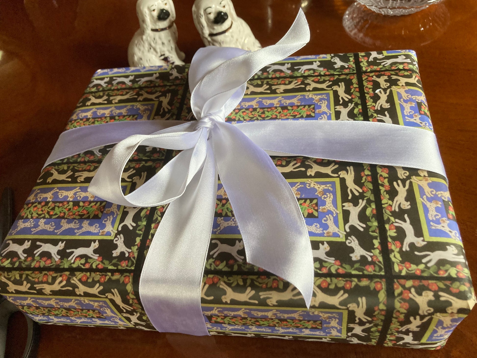 Mockup of wrapped gift with Cats In The Garden gift wrap topped with white ribbon.