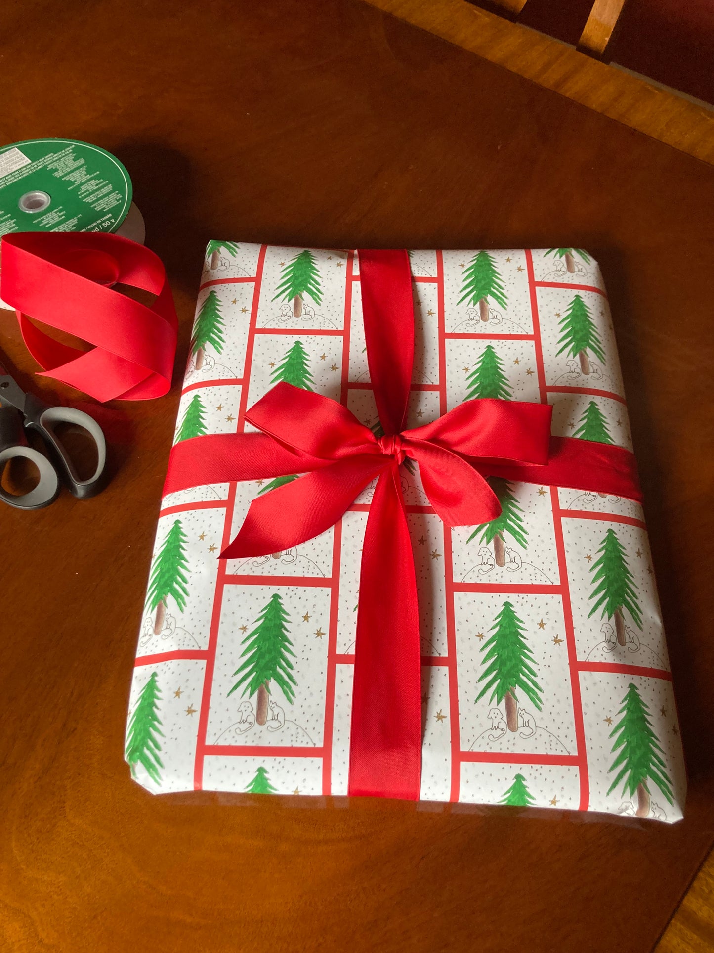 The mock up shows a present wrapped in Under The Tree gift wrap and topped with a cheery red ribbon.