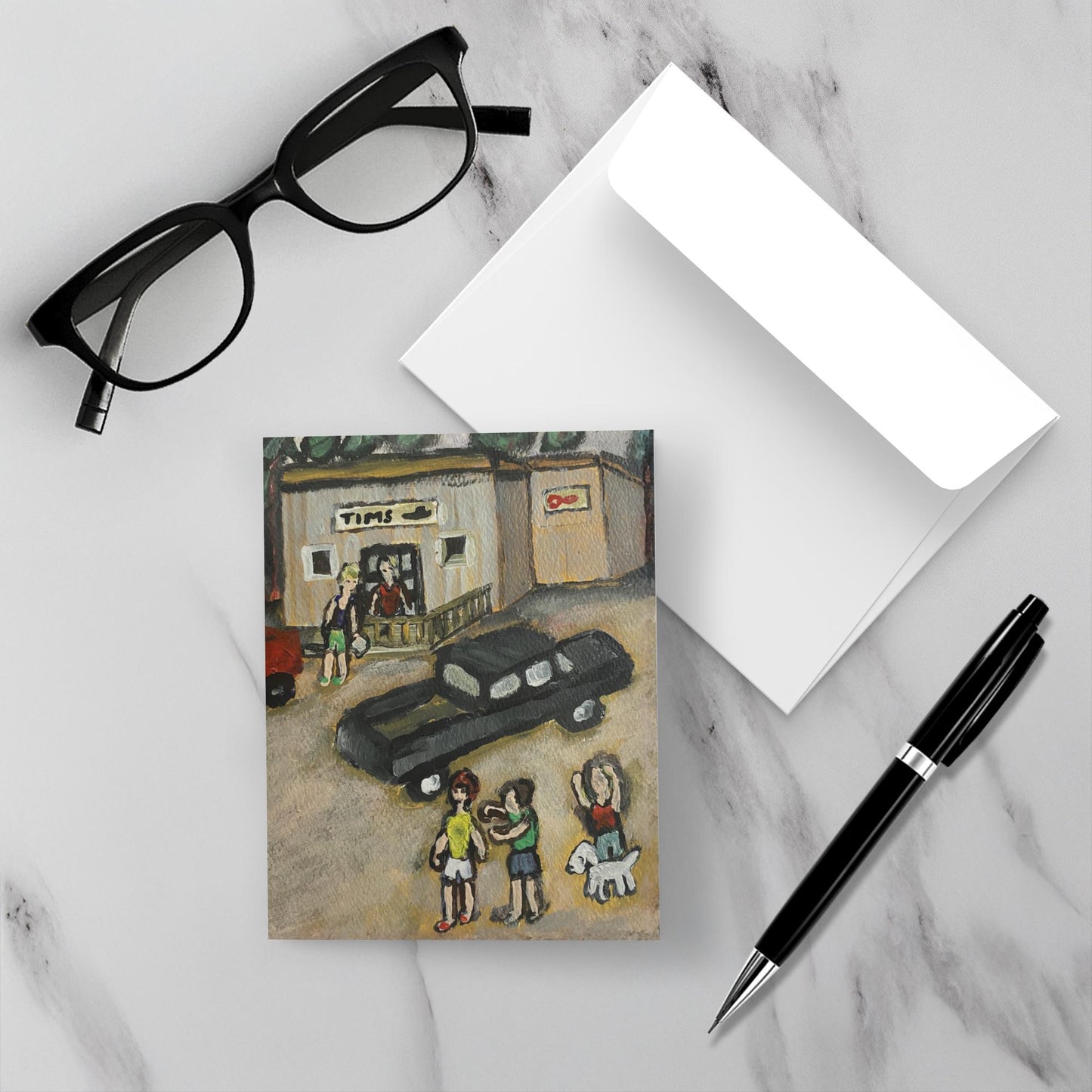 The Island Store notecard on a white marble surface with a pen and eyewear.
