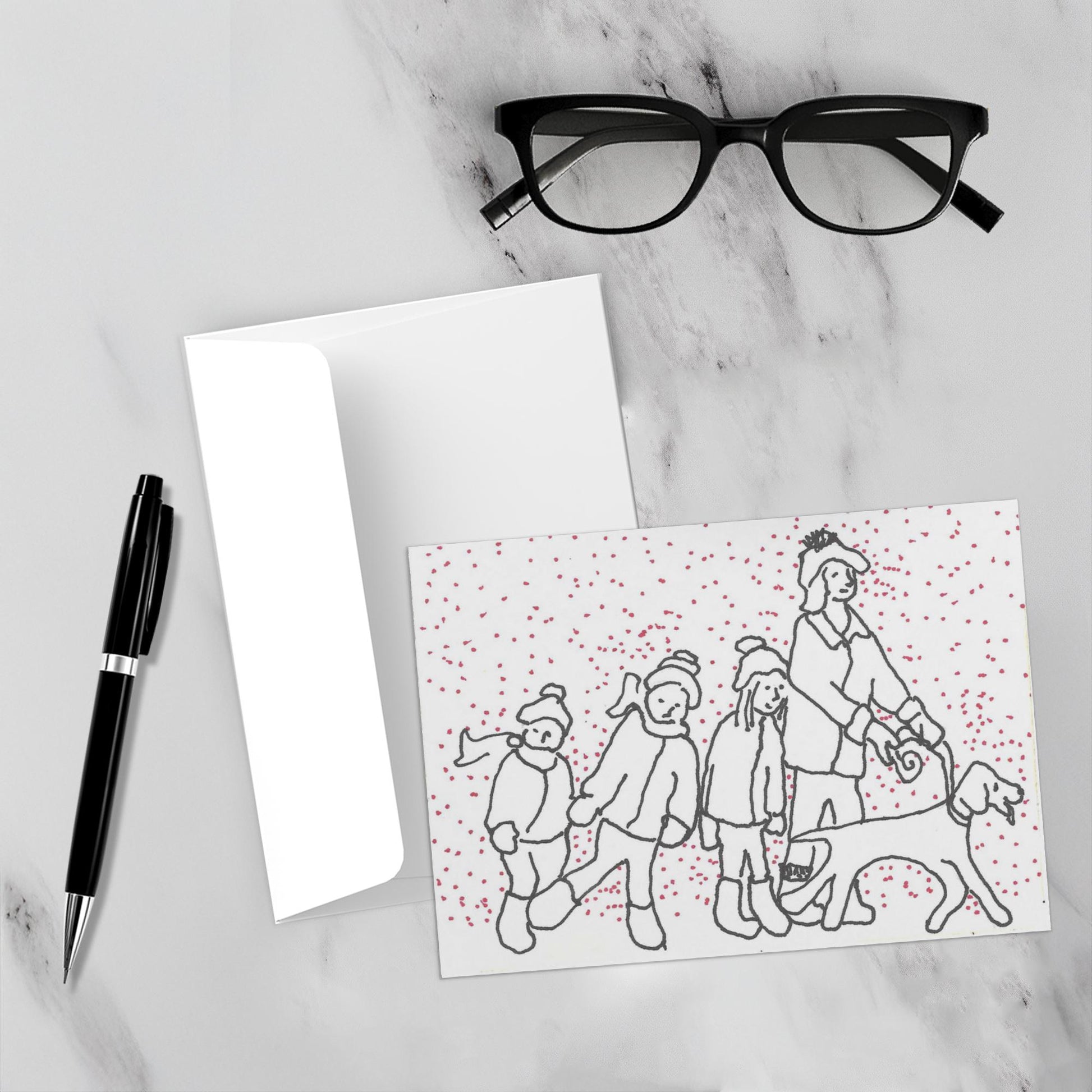 Mockup display showcasing the front of the greeting card Hunter Leads The Way For A Fun Day lying on a gray marble surface along side a white envelope, a pair of black reading glasses and a black pen.