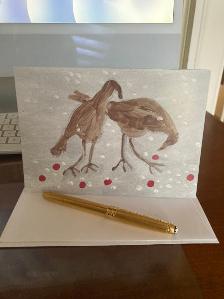 mock up of the front of Birdie Treats winter greeting card with its envelope and a gold pen,