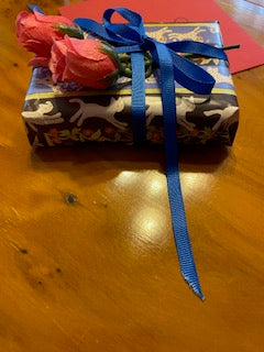 Mockup shows a small gift wrapped with a blue ribbon and roses.