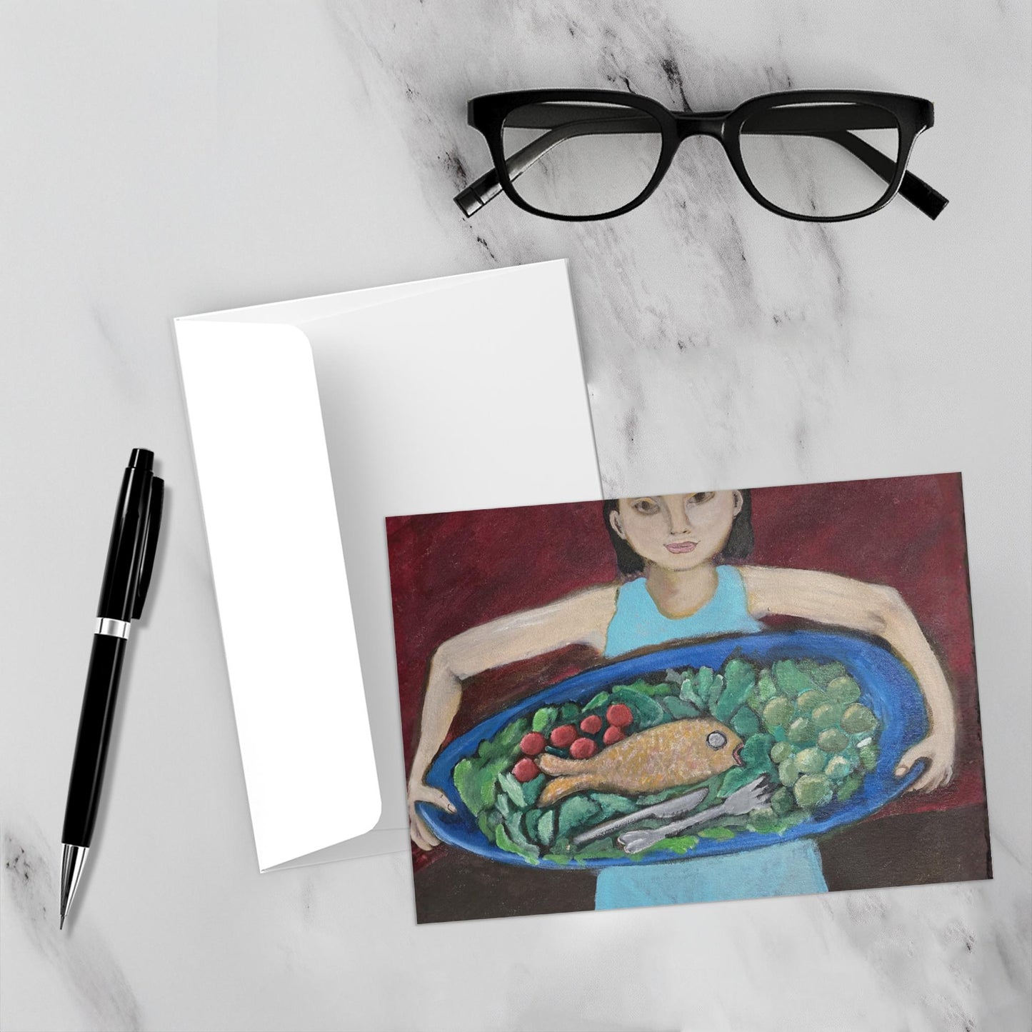 The front of the card Fish Platter Just For You is on a white marble table with its envelope a pen and glasses.