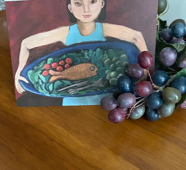 Card with a stylized illustration of a person holding a plate with a fish and vegetables, surrounded by grapes on a wooden surface.