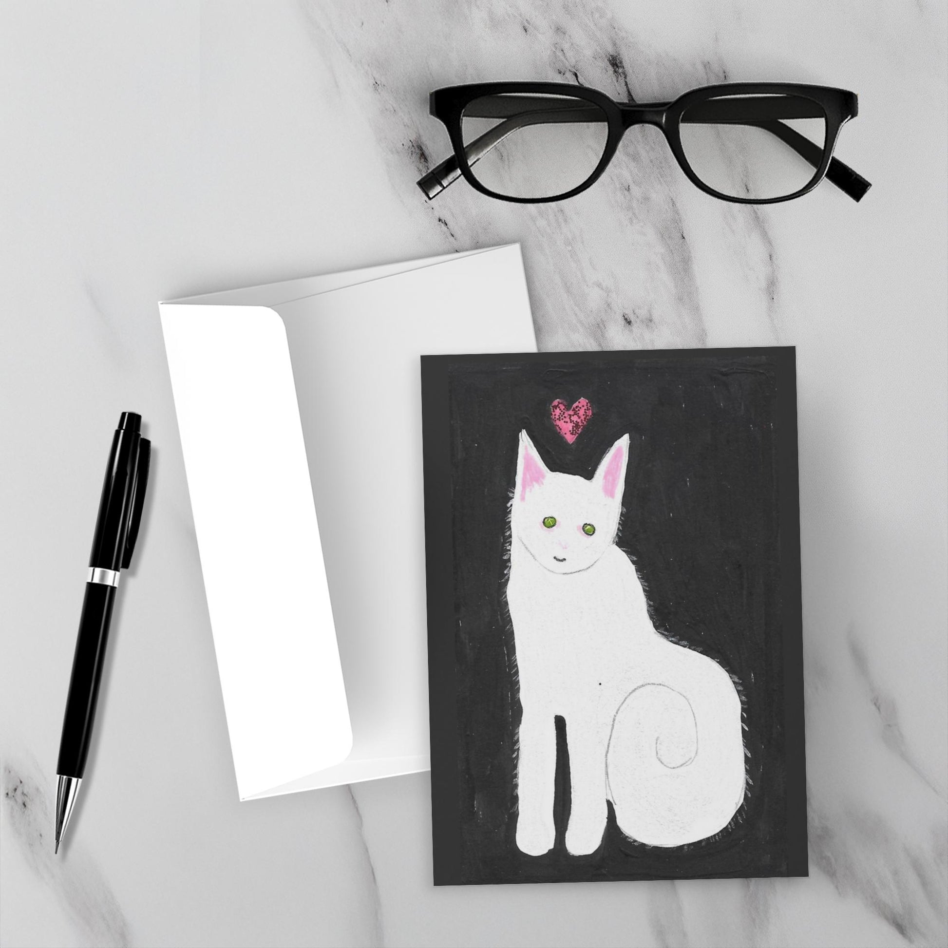 Mockup of the greeting card Love And Kisses Caspar really stand out against the white marble background. Envelope, pen and reading glasses are also shown.