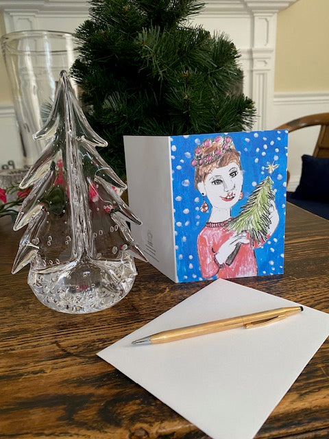 Christmas card with a decorative envelope on a table with a pen and crystal ornament.