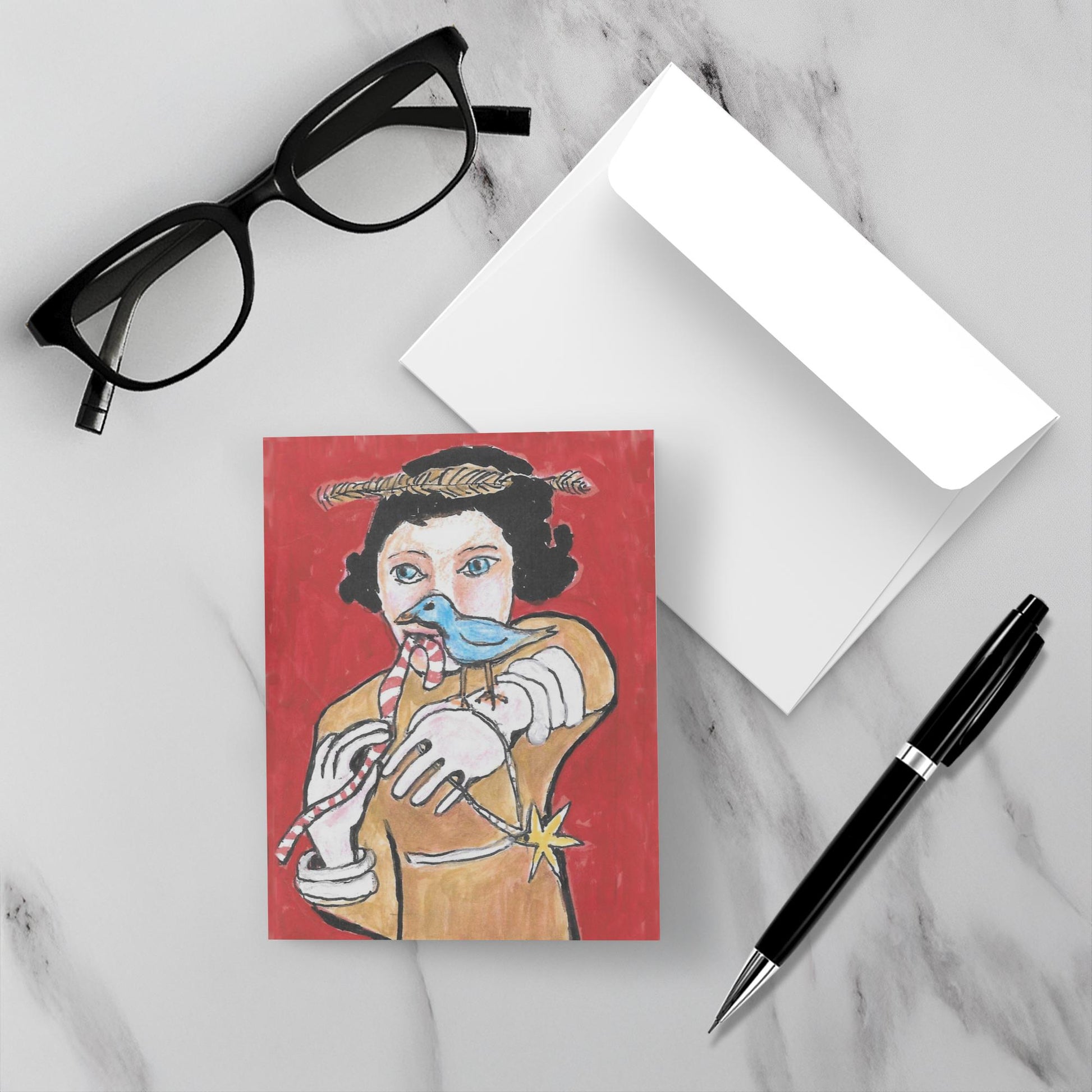 mockup of the Red Holiday Girl With Bird holiday greeting card shown atop white envelope and beside black reading glasses and black pen to give visual context as to size.