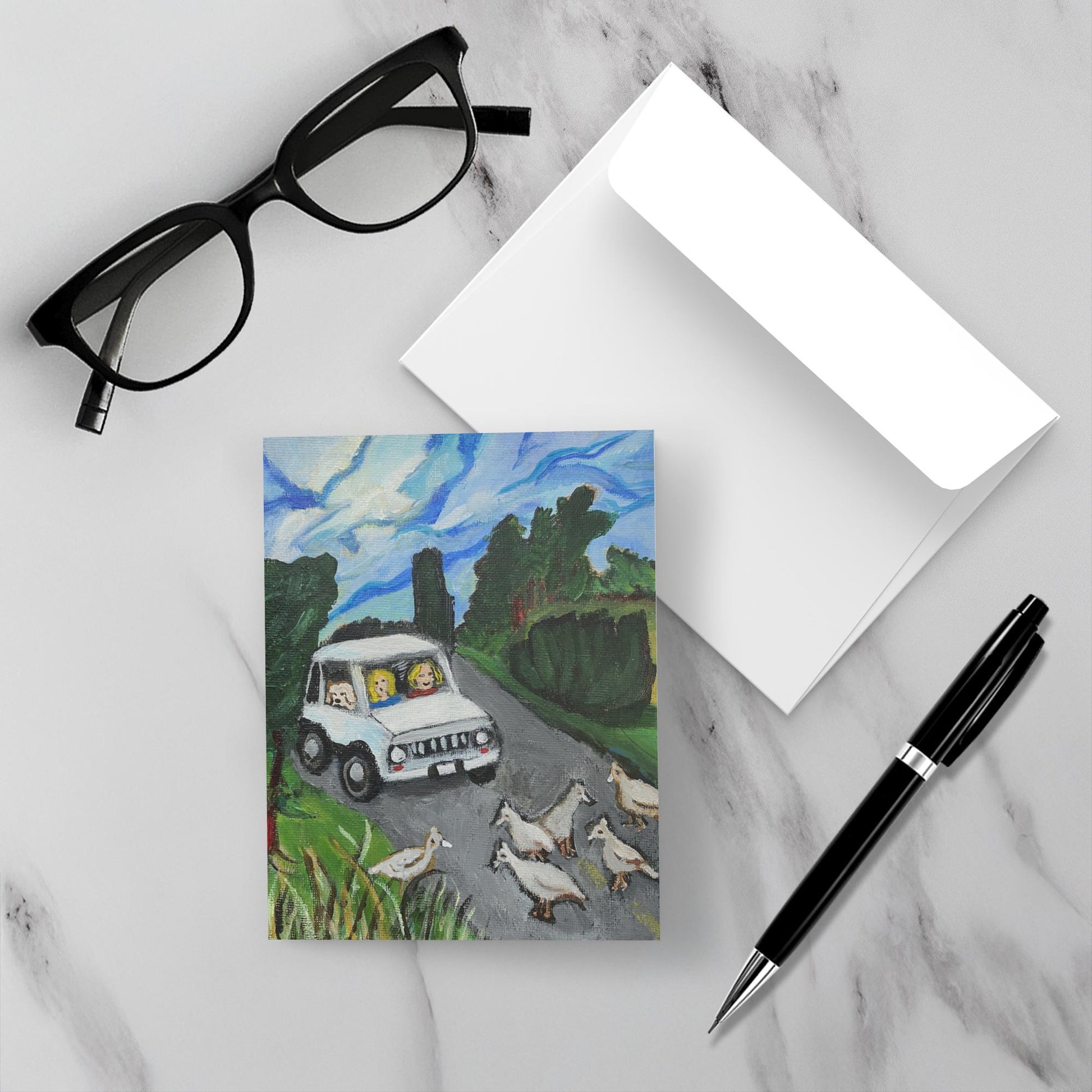 Pavement Patrol notecard on a white marble surface with a pen, glasses and its envelope.