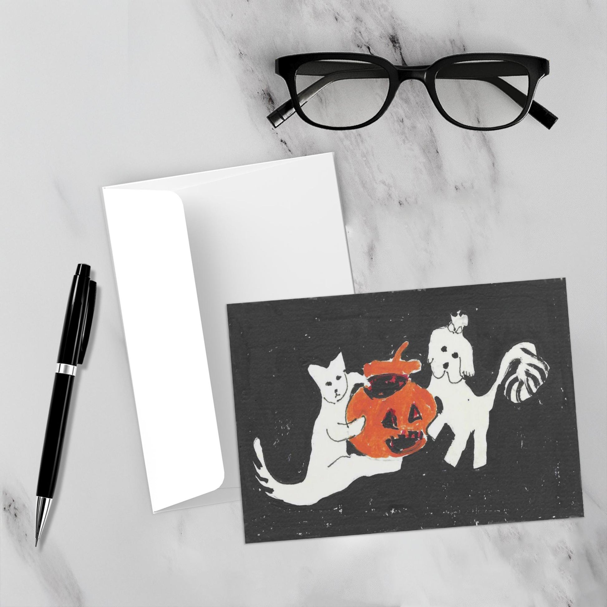 Mock up of the front of this adorable and whimsical Halloween card along with its envelope on a white marble surface.
