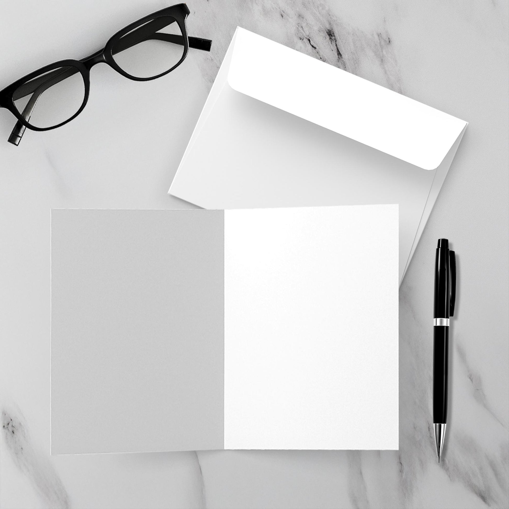 A mock up of the white envelope and blank inside of Firepit Fun! greeting card set on a white marble background.